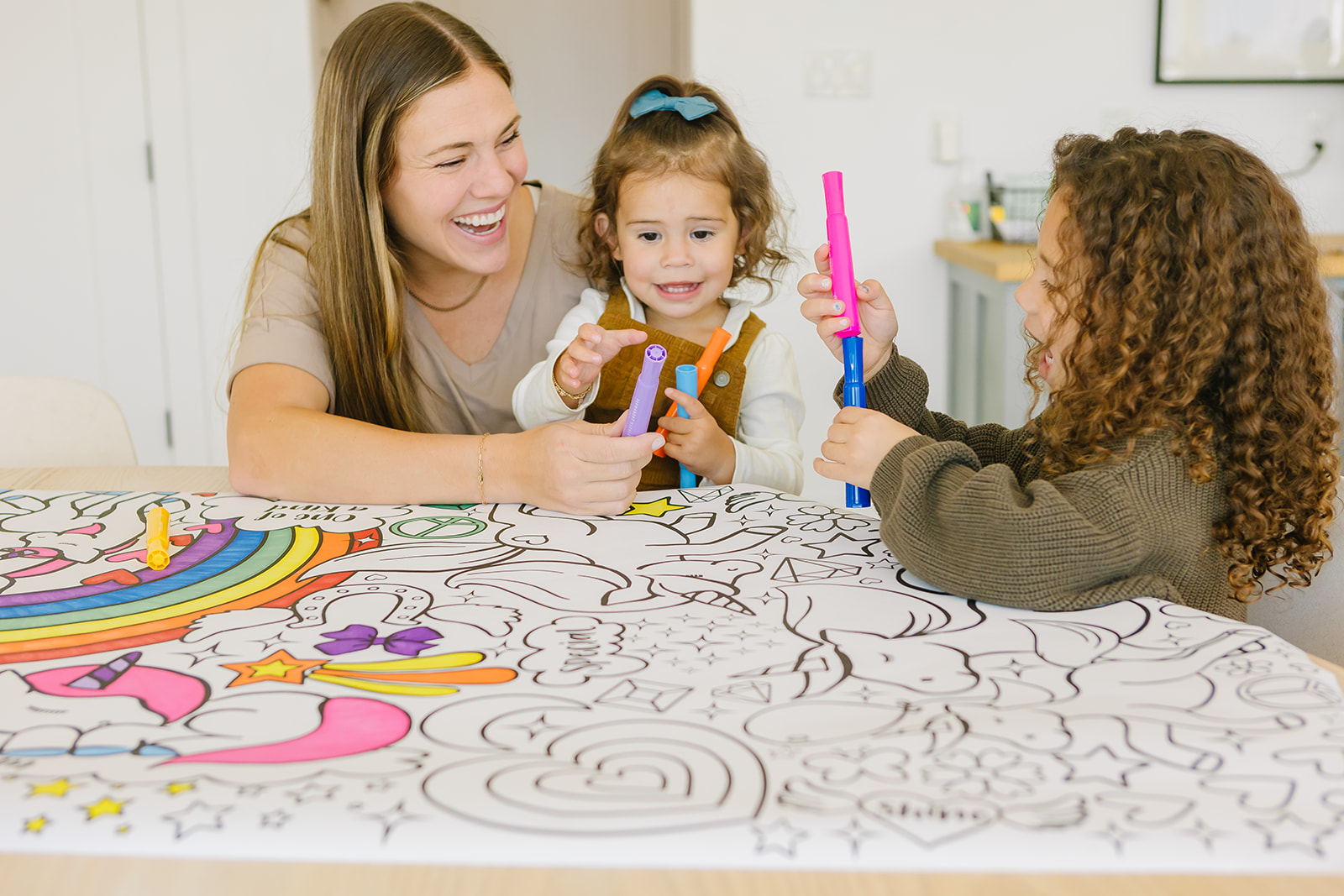 Mom and kids laughing while coloring a giant banner together